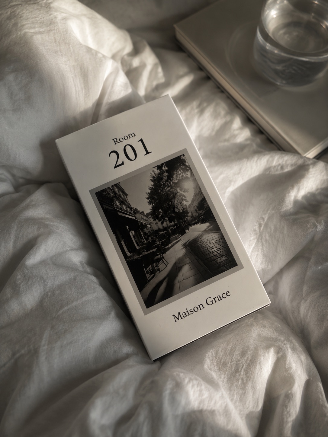白い寝具の上に置かれたRoom 201のパッケージ